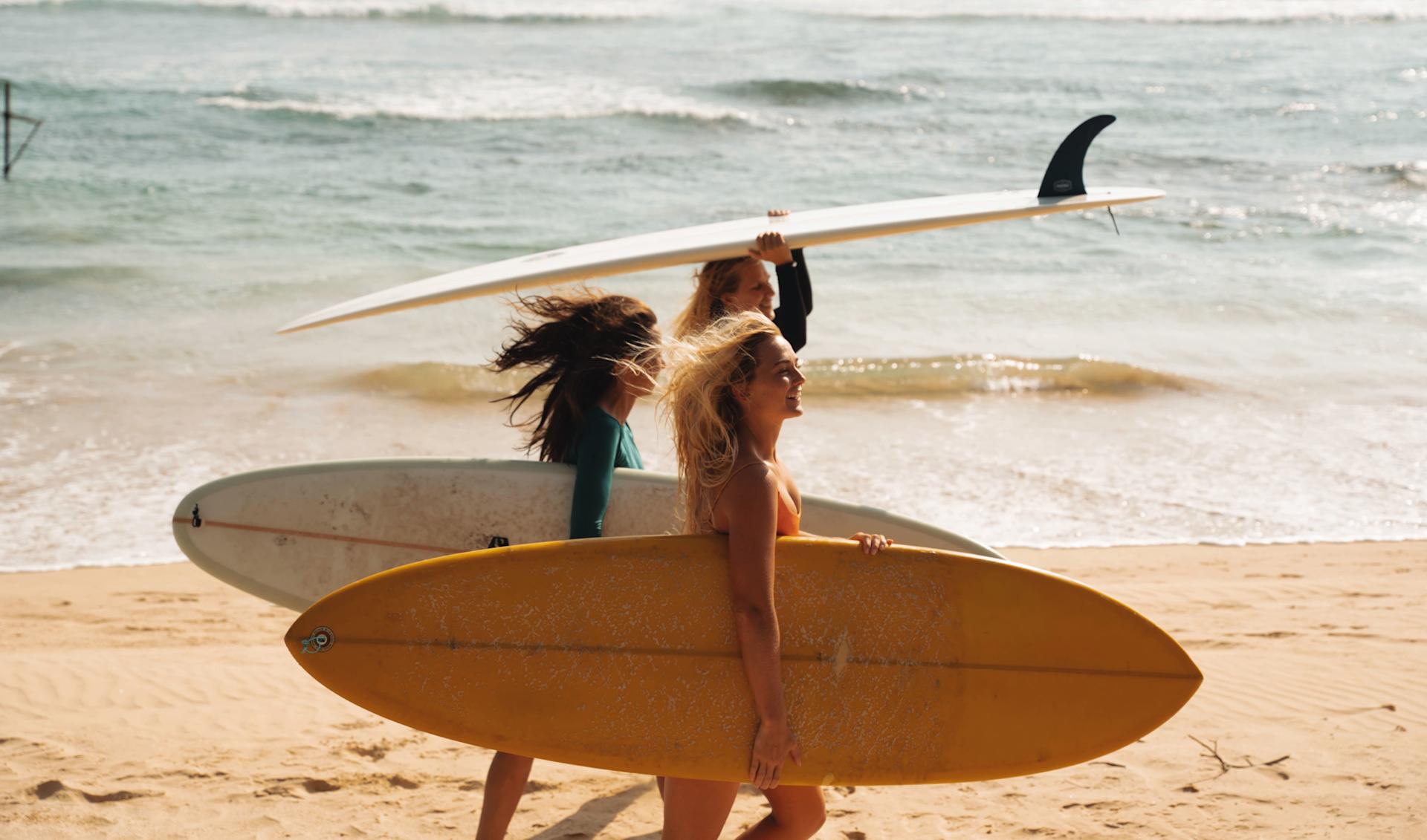 Girls walking on the beach with surfboard