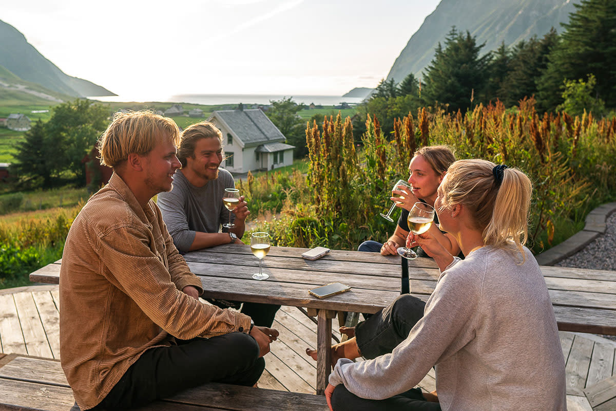 Friends drinking wine in sunset at Hoddevik Lapoint