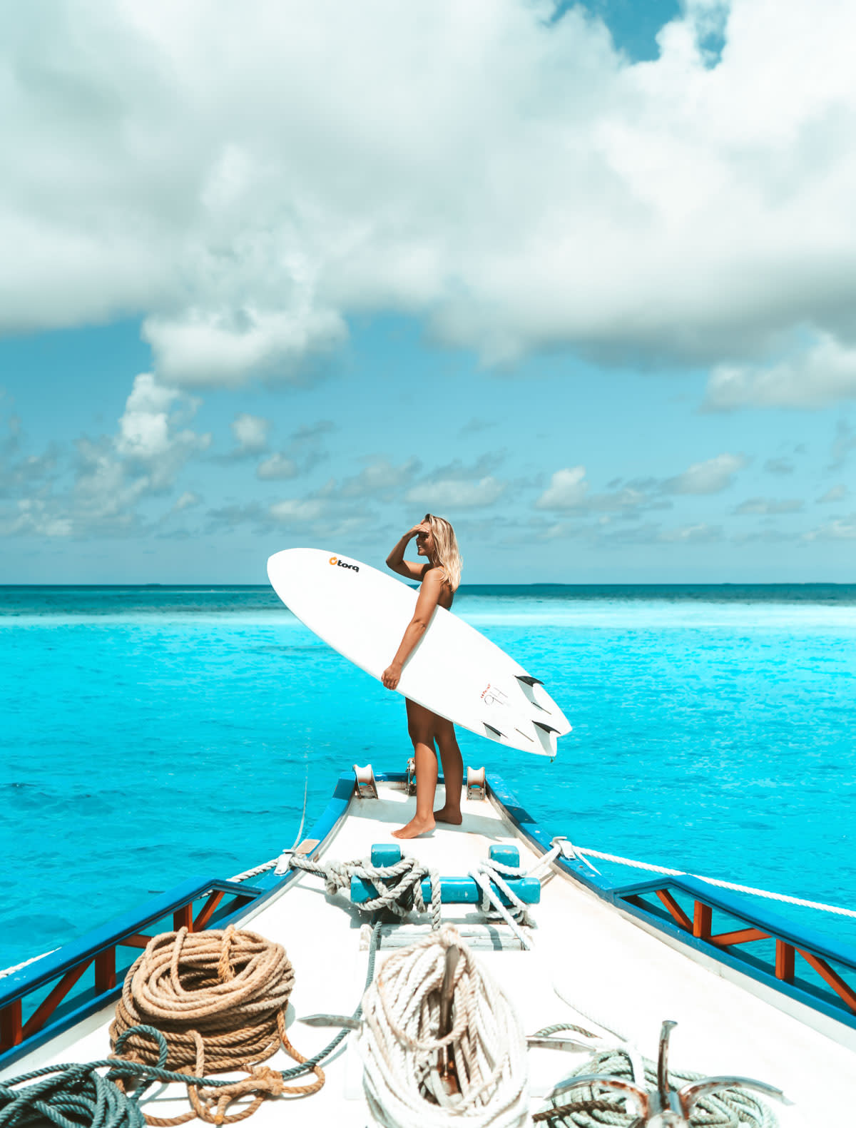 Girl on boat with surfboard, maldives