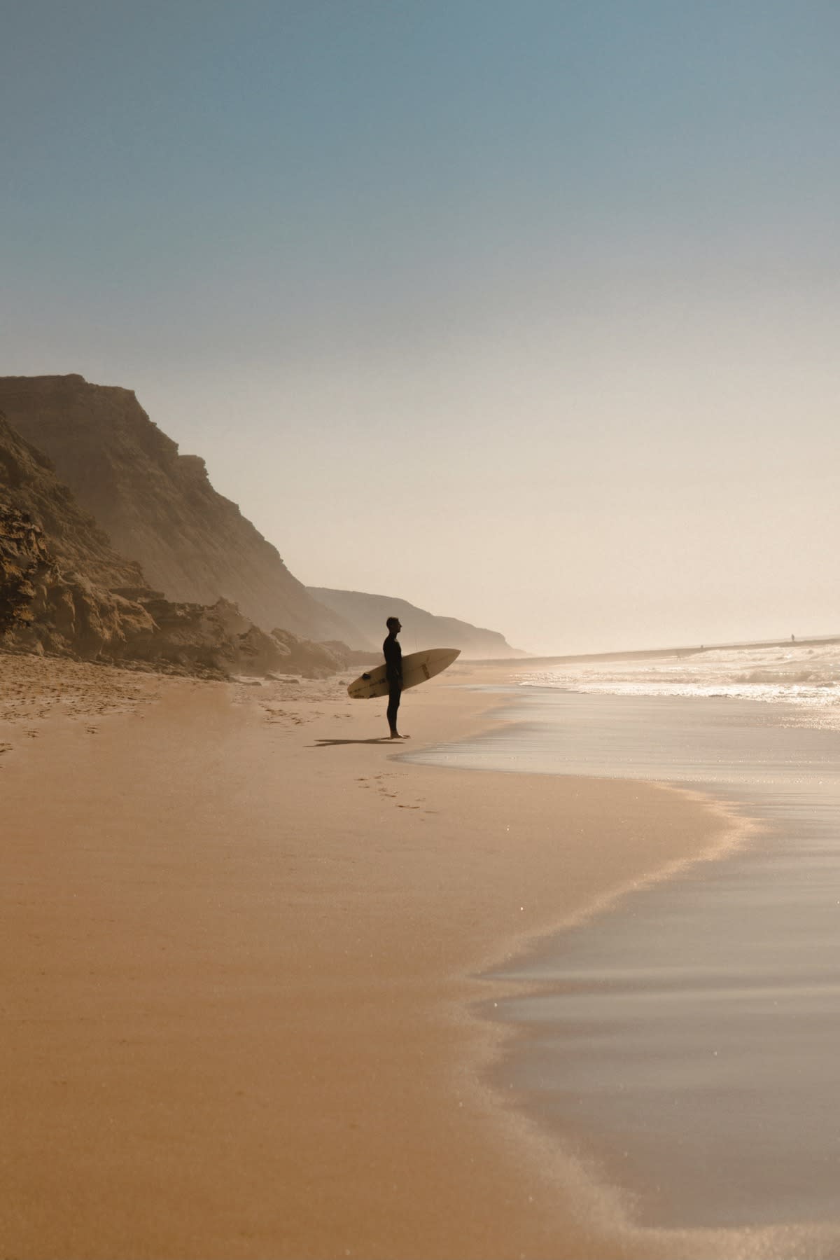 Surfer looking out to lineup from the beach in Ericeira