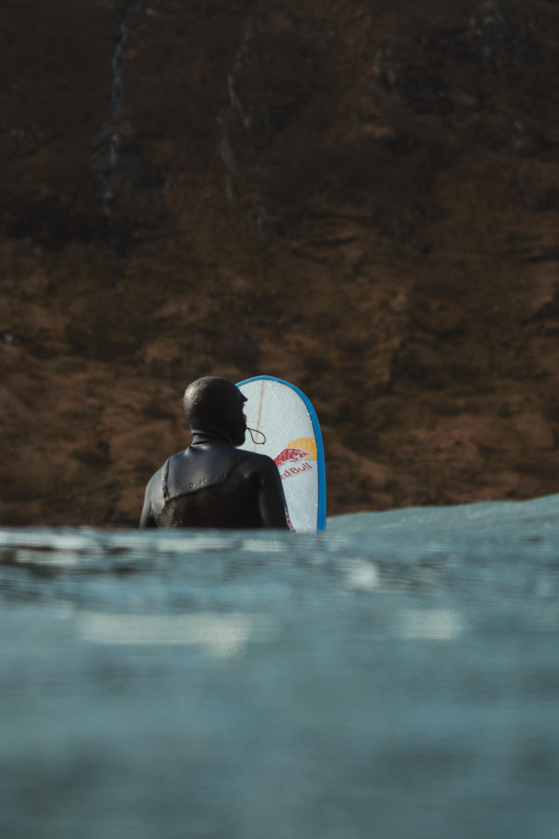 Surfer sitting in the lineup in Hoddevik by the cliff