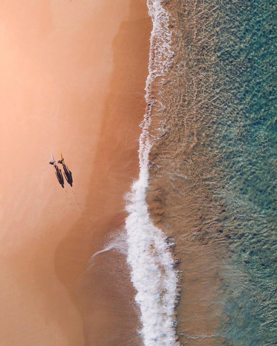 surfers on beach drone shot